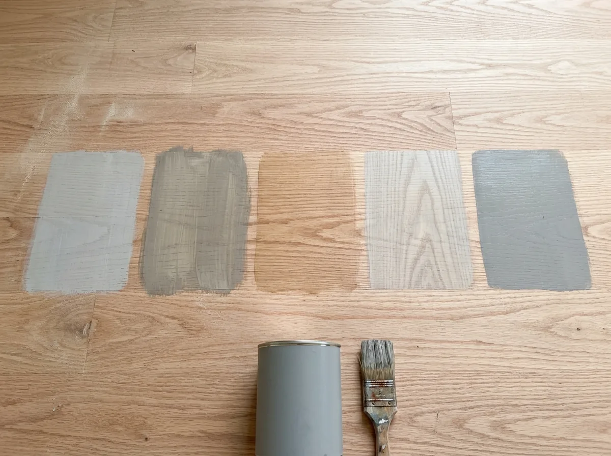 Row of sample patches in pale gray, driftwood and white tones brushed across a sanded oak floor